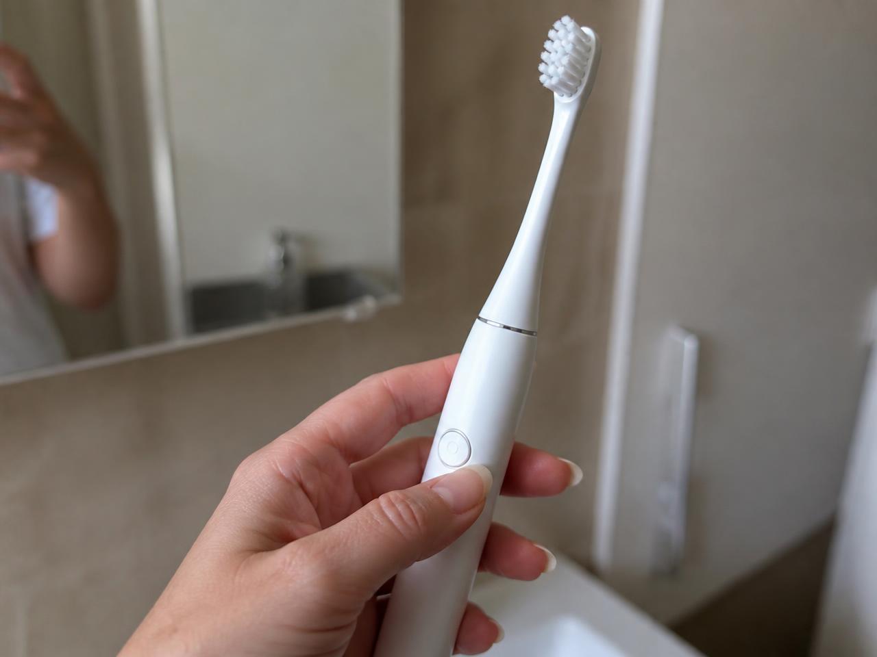 Mano che impugna il manico del SonicX PRO davanti allo specchio del bagno